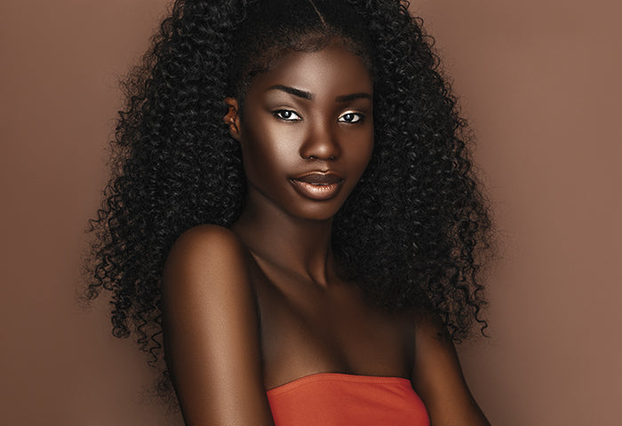 A woman looking at the camera, she has long curly black hair